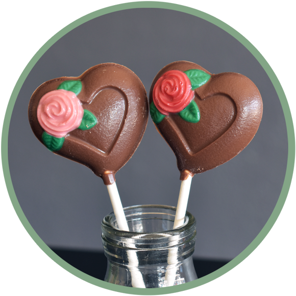 Chocolate heart lollipops with a pink or red rose. Hand molded chocolates from Kalona, Iowa.