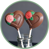 Chocolate heart lollipops with a pink or red rose. Hand molded chocolates from Kalona, Iowa.