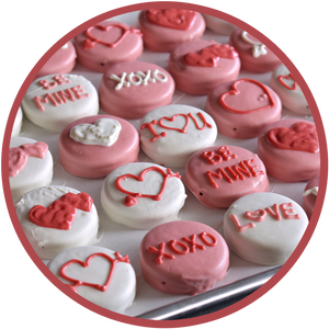 A tray of hand decorated chocolate covered Oreos for valentine's day. Oreos are decorated with hearts, love, and be mine.