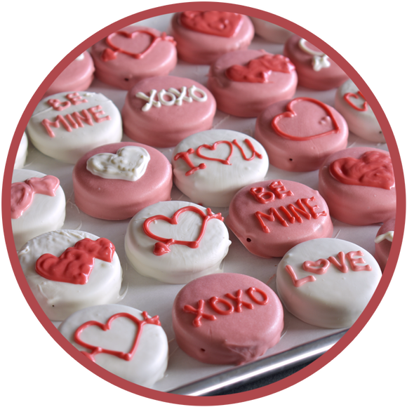 A tray of hand decorated chocolate covered Oreos for valentine's day. Oreos are decorated with hearts, love, and be mine.