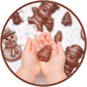 A child holds a mini molded christmas chocolate.