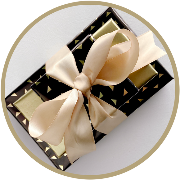 Classy small gift bundle of boxes of chocolate wrapped in gold satin ribbon. 